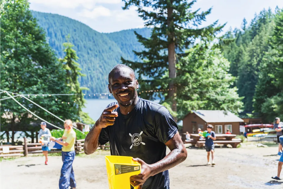 Voluntario sonriendo en un campamento junto a un lago en Canadá