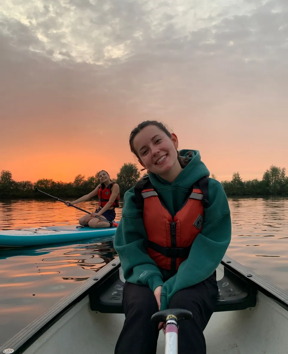Voluntaria con chaleco salvavidas en una canoa al atardecer