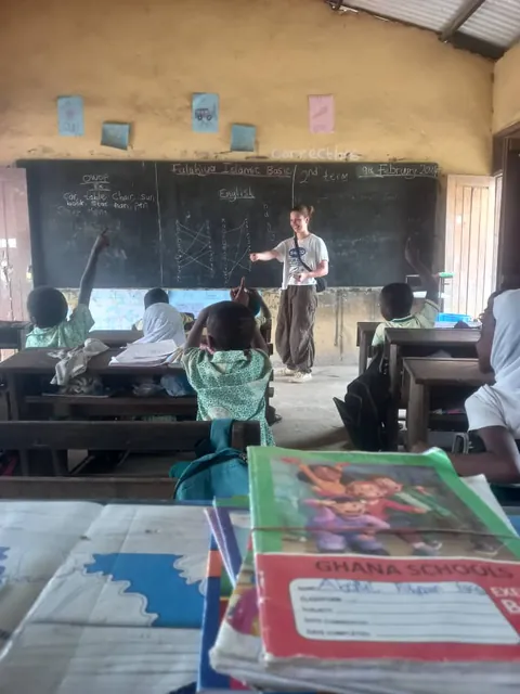 Sala de clases en Ghana con un voluntario frente a la pizarra