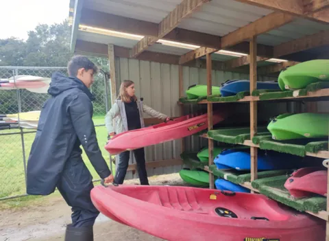 Voluntarios ordenando kayaks en un centro al aire libre