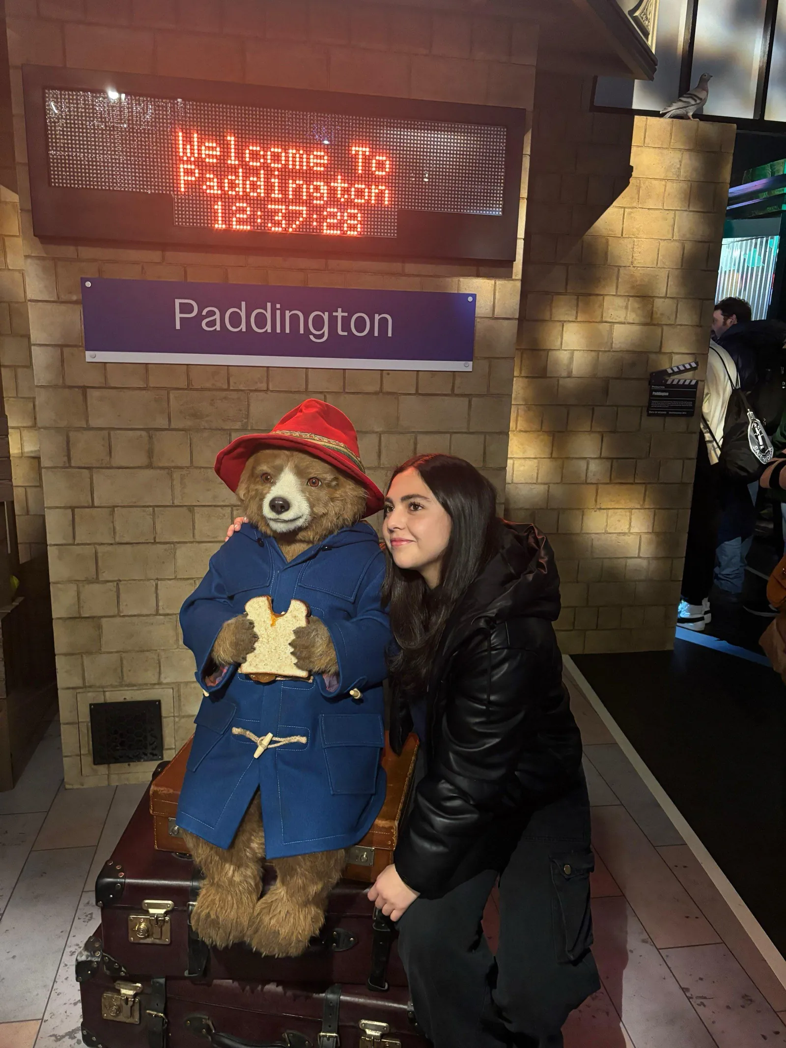 Voluntaria junto a la estatua del oso Paddington en la estación de Paddington, Londres