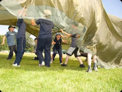 Voluntarios jugando con un paracaídas de colores en un campamento
