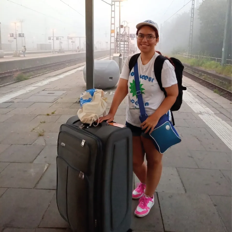 Voluntaria con su maleta en el andén de una estación de tren